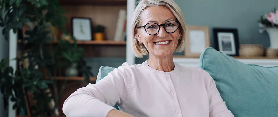 Confident older woman sitting on the couch smiling in natural light