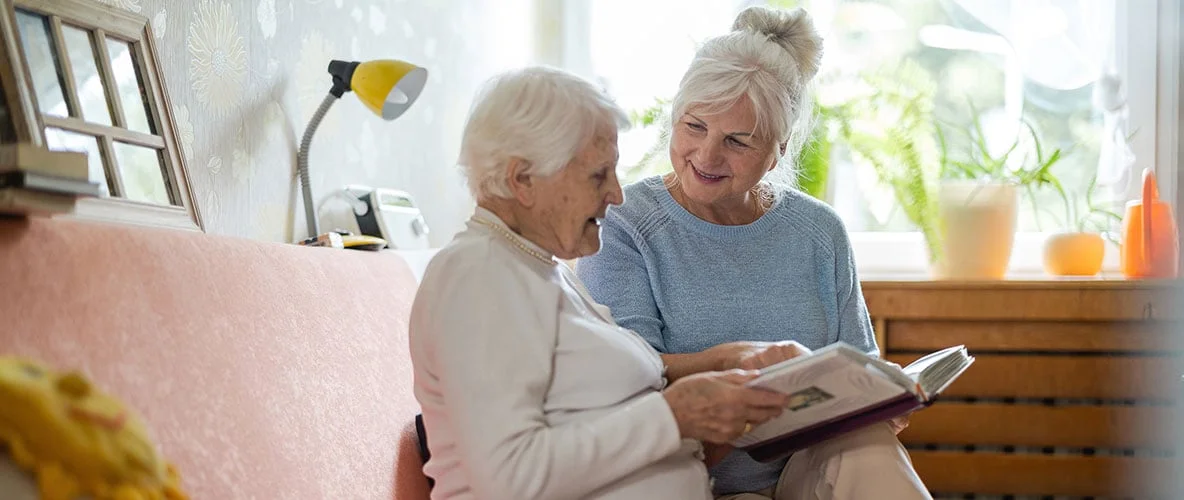 Two senior women sharing a book