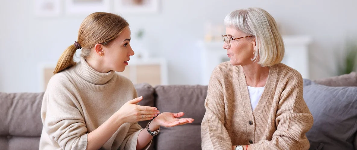 Adult daughter having caring conversation with elderly parent