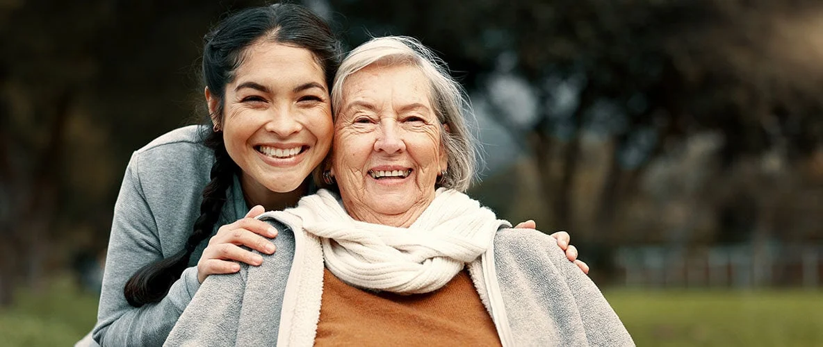 Adult daughter posing for a photo with elderly woman